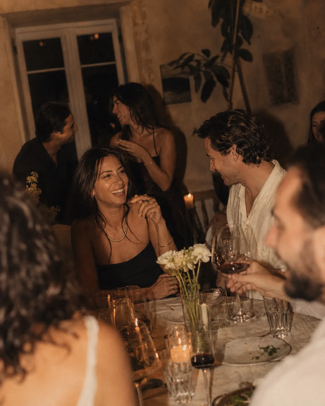 Des invités partagent un moment chaleureux autour d'une table pendant une soirée.